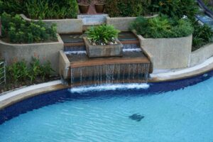 a stunning pool waterfall surrounded by lush landscaping
