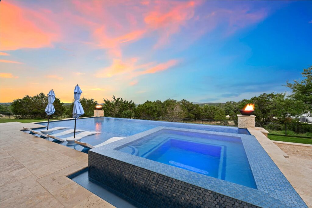 a luxury pool and hot tub during a rich sunset
