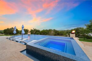 a luxury pool and hot tub during a rich sunset