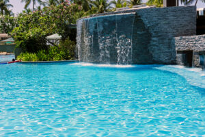 a beautiful stone pool waterfall pouring into a luxury pool